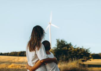 Woman and little child hugging in a windfarm.
