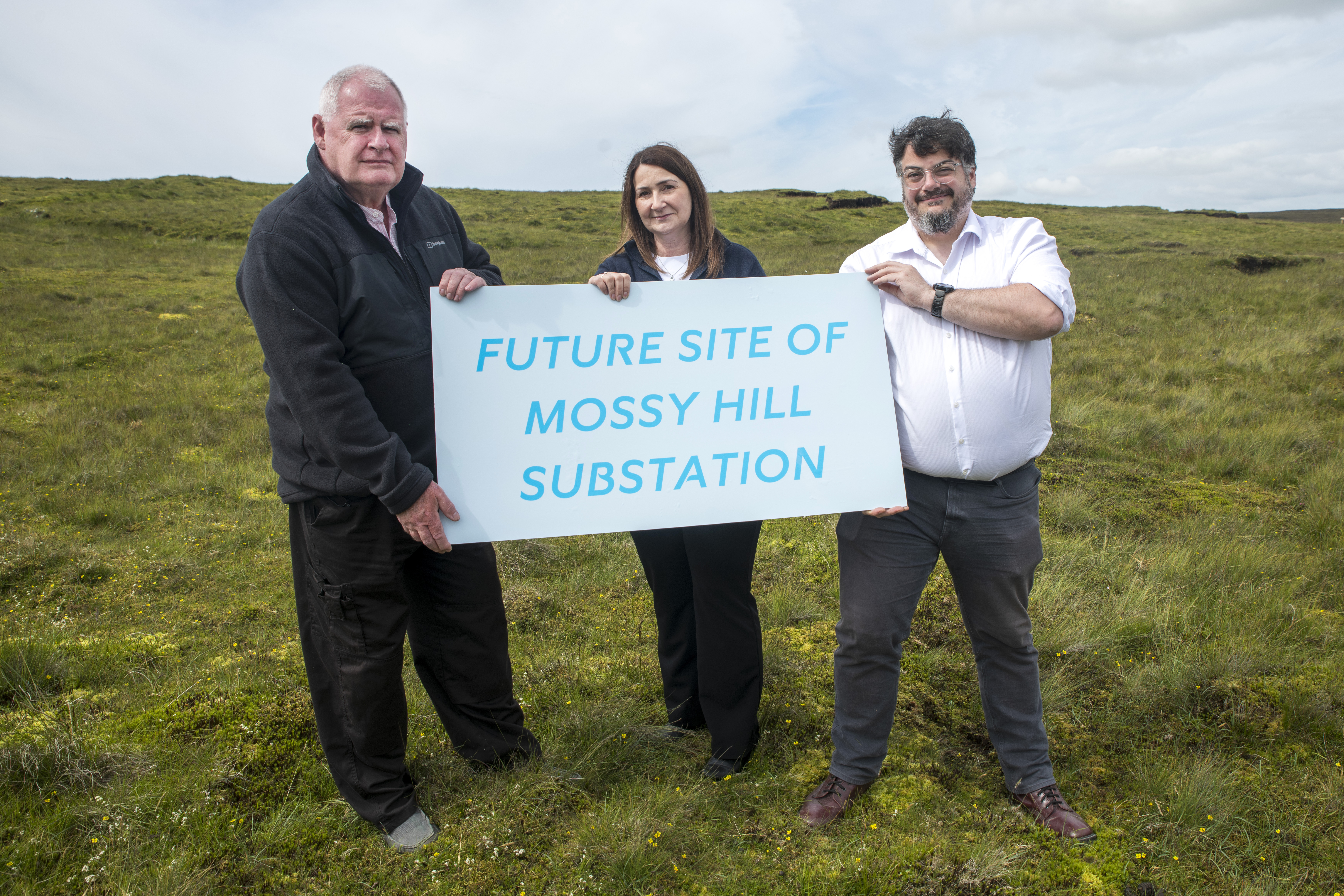 Three members of Statkraft staff stand holding a sign reading Future Site of Mossy Hill Substation