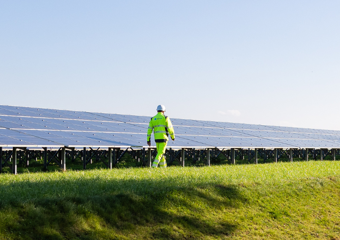 Man walking next to a solar panel